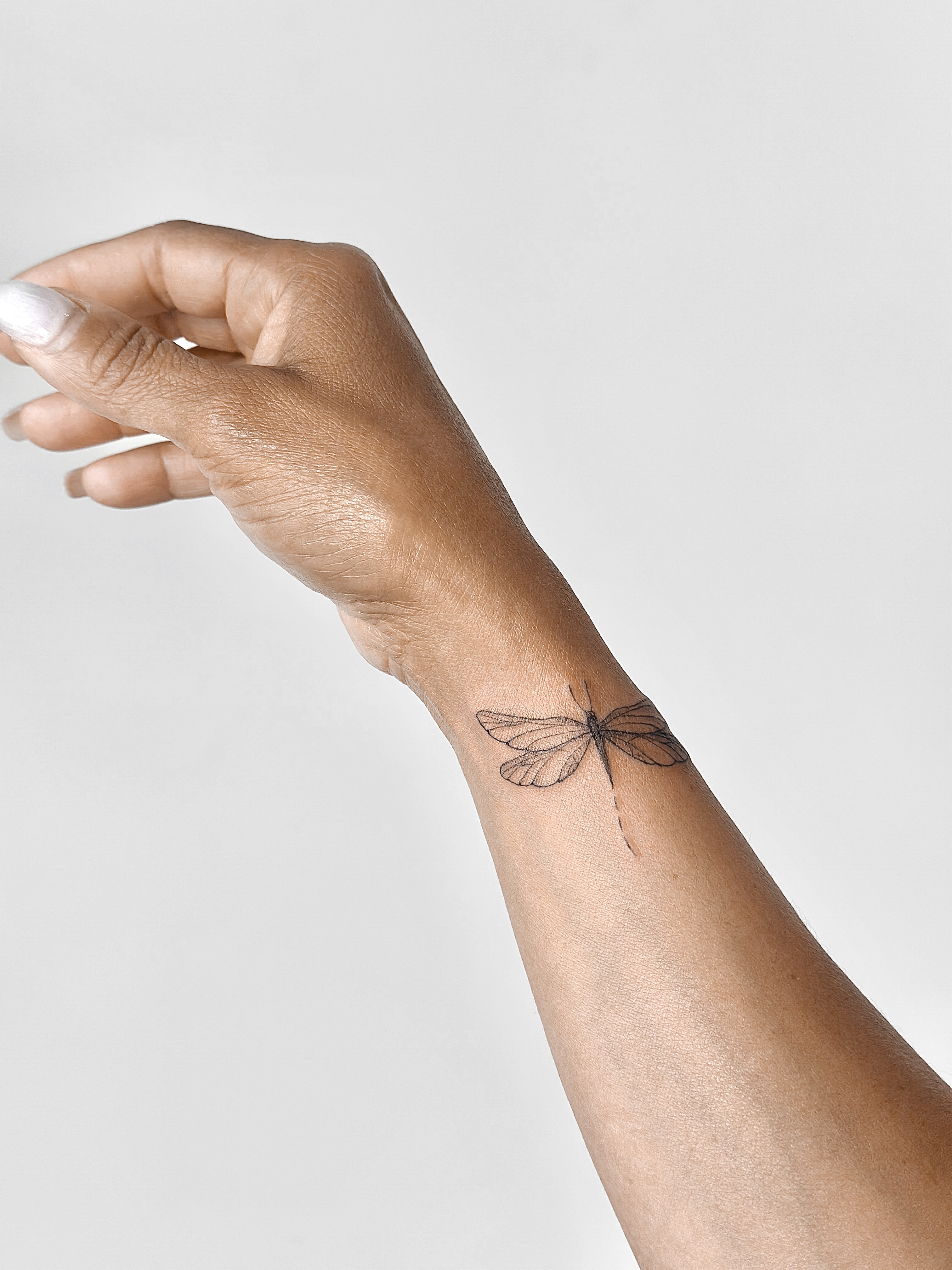 Delicate dragonfly wrist tattoo by CHA